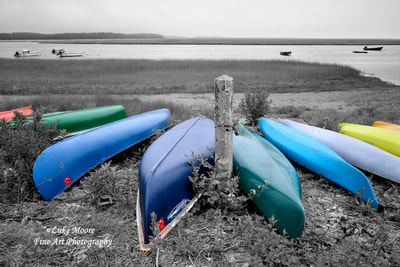 A colorful collection of kayaks and canoes resting in a Cape Cod salt marsh overlooking the scenic Salt Pond Bay in Eastham, Massachusetts New England. These brightly-colored boats give hope and dreams of adventure on a cloudy summer day. 