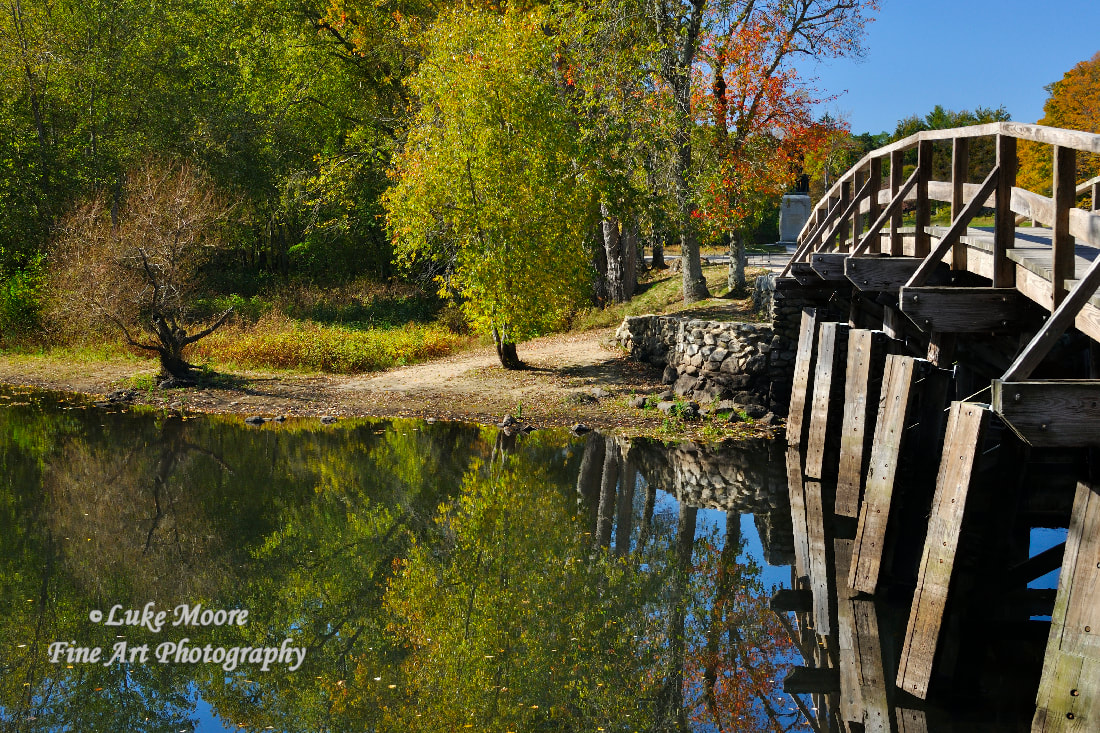 A colorful autumn landscape photograph of the Old North Bridge located in Minute Man Park in Concord, Massachusetts, Middlesex County. 
